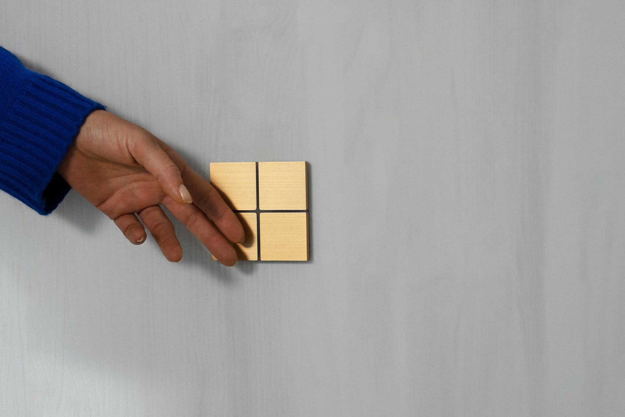 A hand pressing a brushed brass Basalte Sentido keypad