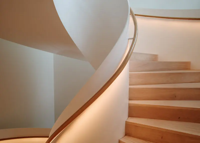 Curved staircase with a softly lit handrail