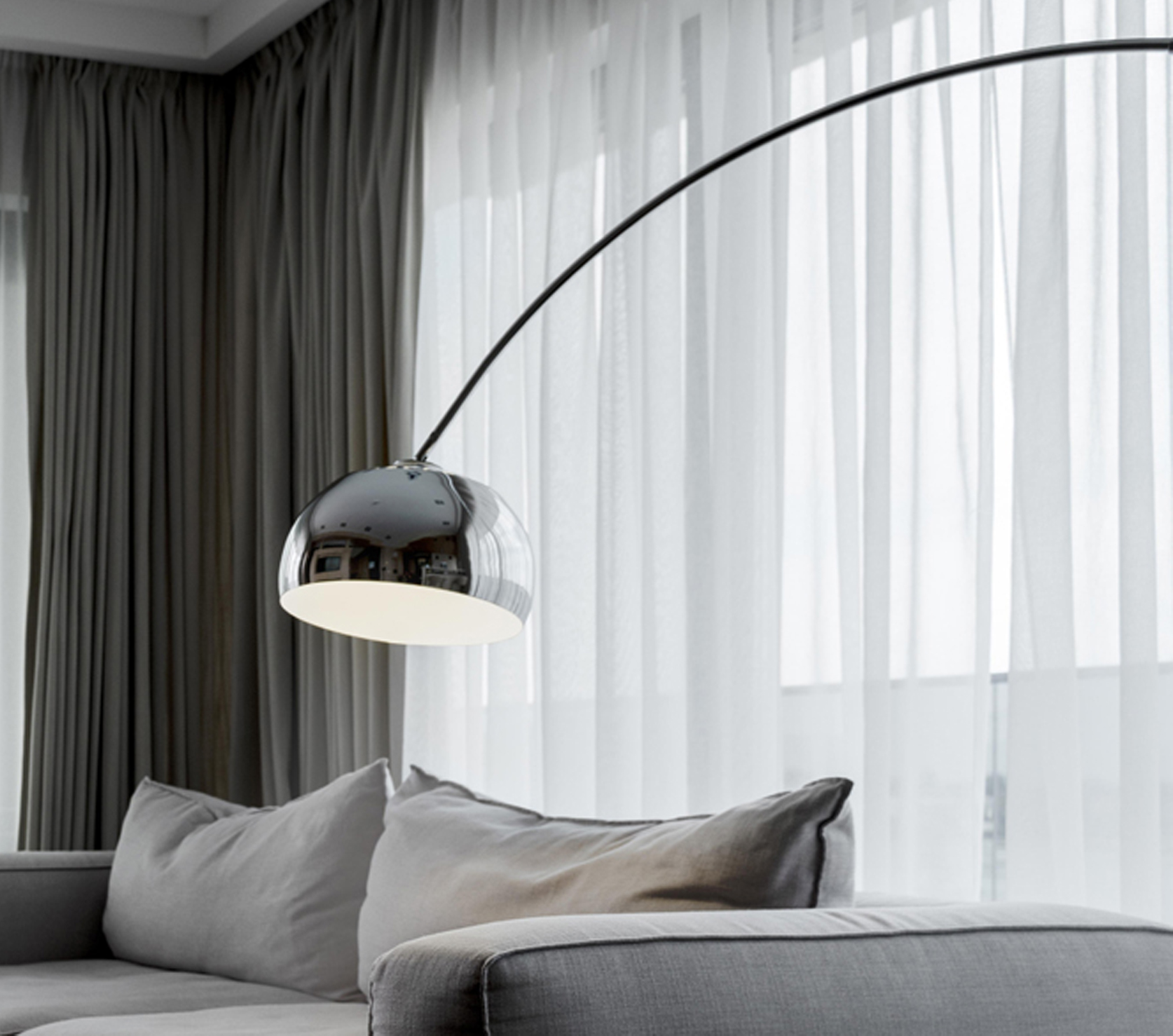 Sofa and arc floor lamp in front of sheer curtains